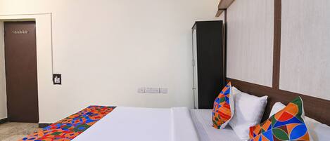 A hotel room with a bed, a nightstand, a wardrobe, and a door.