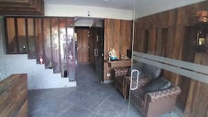 Un intérieur moderne avec un escalier menant à un deuxième étage, un coin salon avec un banc rembourré et une petite cuisine équipée d’un réfrigérateur et agrémentée d’un objet décoratif posé sur le plan de travail.