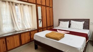 Een slaapkamer met een bed, een houten garderobe en een raam met gordijnen.