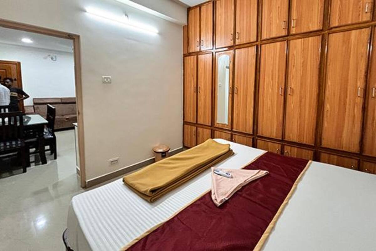 A bedroom with a bed, a wooden wardrobe, and a small table with chairs.
