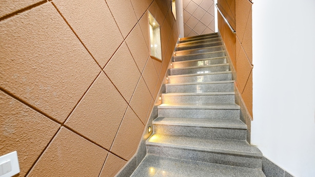 A staircase with a textured wall on one side and a plain wall on the other, leading to an upper floor. - FabHotel The Cozy Cloud (New Delhi)