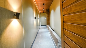 A hallway with wooden paneling on one side, a tiled floor, and recessed lighting. - FabHotel The Cozy Cloud (New Delhi)