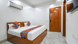 A modern hotel room with a wooden bed, white walls, a marble floor, and a wooden door. - FabHotel The Cozy Cloud (New Delhi)