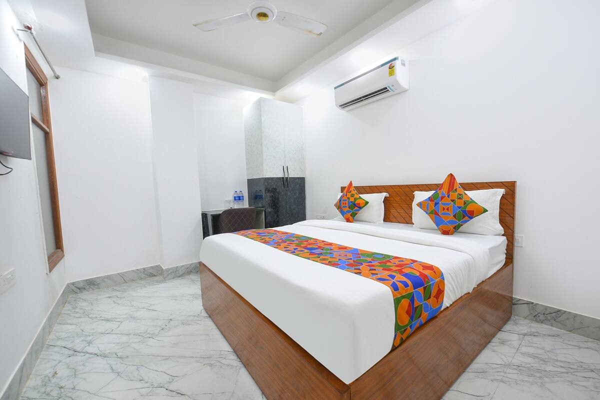 A hotel room with a large bed, a wooden headboard, a marble floor, and a ceiling fan.