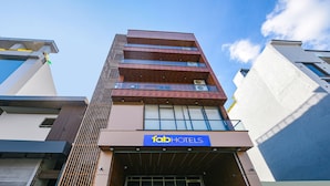 A multi-story building with a 'fab hotels' sign, featuring a modern design with a mix of glass and concrete facades, and a visible entrance with a metal gate. - FabHotel The Cozy Cloud (New Delhi)
