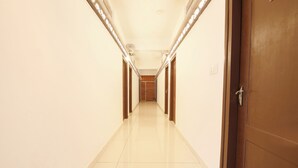 A long, narrow hallway with a shiny floor and wooden doors on both sides. - Fabhotel Raj (Madikeri)