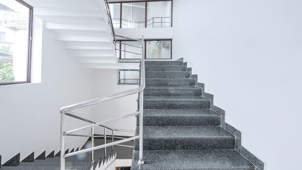A modern staircase with metal railings and a glass railing on the upper landing. - Fabhotel Raj (Madikeri)
