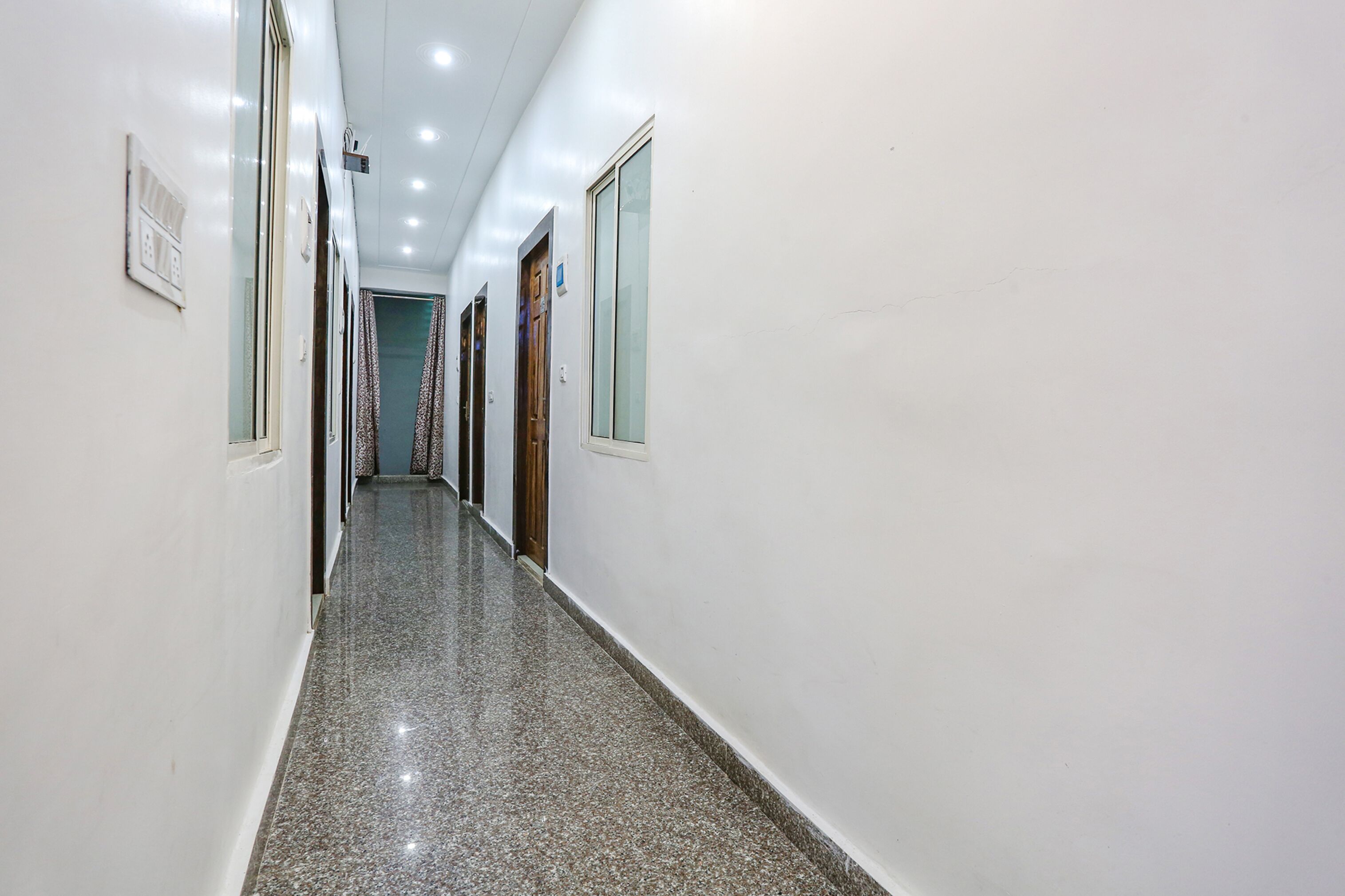 A long, narrow hallway with white walls and a polished granite floor.