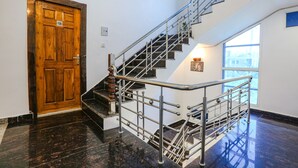 A wooden door with a number plate, a metal staircase with a handrail, and a window with a view of the outside. - Fabhotel Sangita Dham (Mathura)