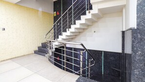 A modern staircase with a metal handrail, white steps, and a marble wall. - FabExpress NK Comforts (Bengaluru)