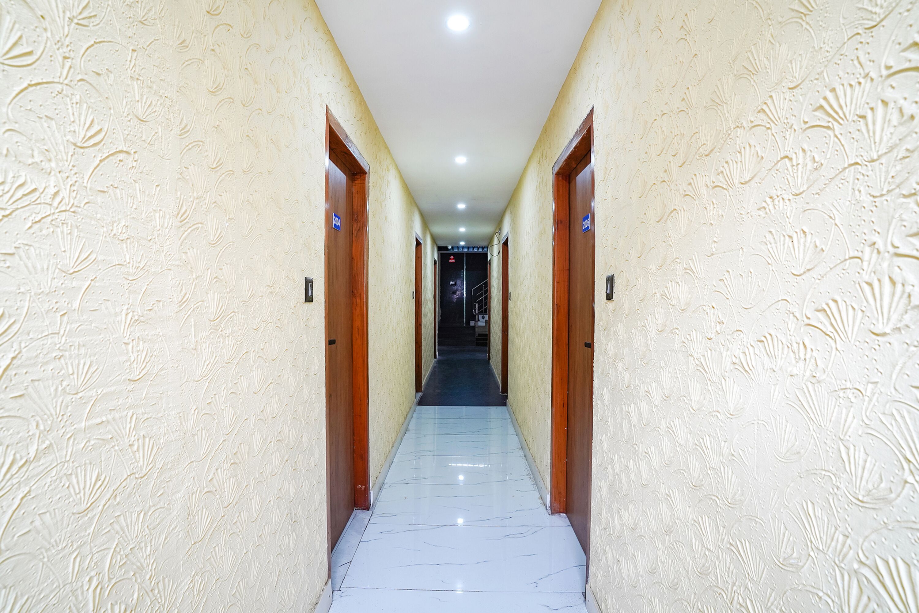 A hallway with textured walls and wooden doors, leading to a staircase.