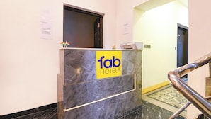 Una recepción con encimera de mármol, un cartel de 'fab hotels' y una pequeña bandera india.