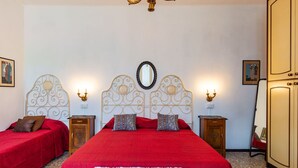 A hotel room with two beds, a chandelier, a mirror, and a wardrobe.