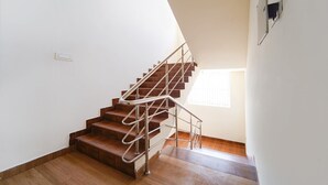 Un escalier avec des marches en bois et des rampes en métal, menant à un palier doté d’une fenêtre.