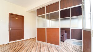 Une pièce avec une porte marron, un sol carrelé et une cloison en bois dotée de panneaux de verre.
