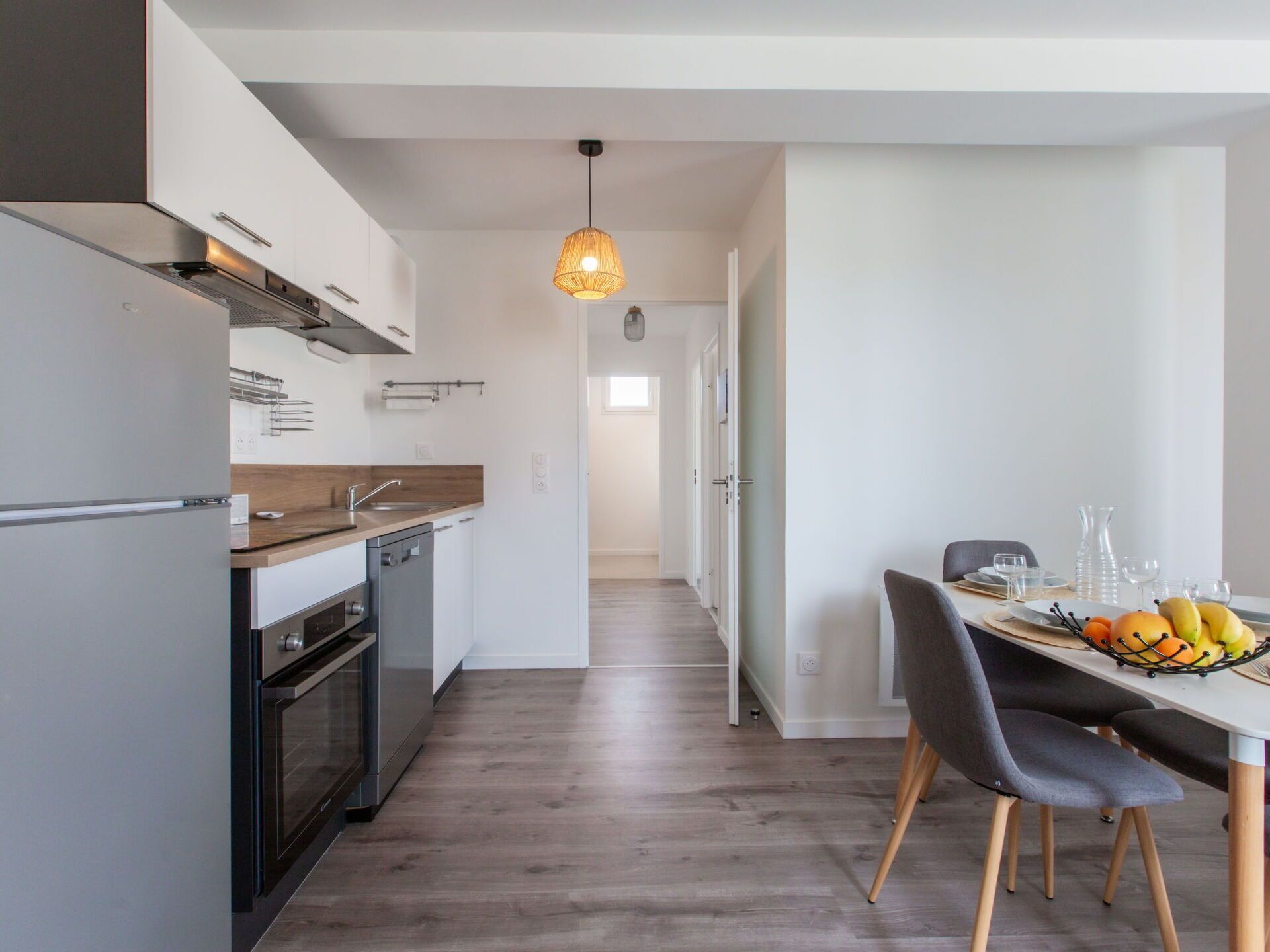 A modern kitchen with a wooden countertop, stainless steel appliances, and a pendant light.