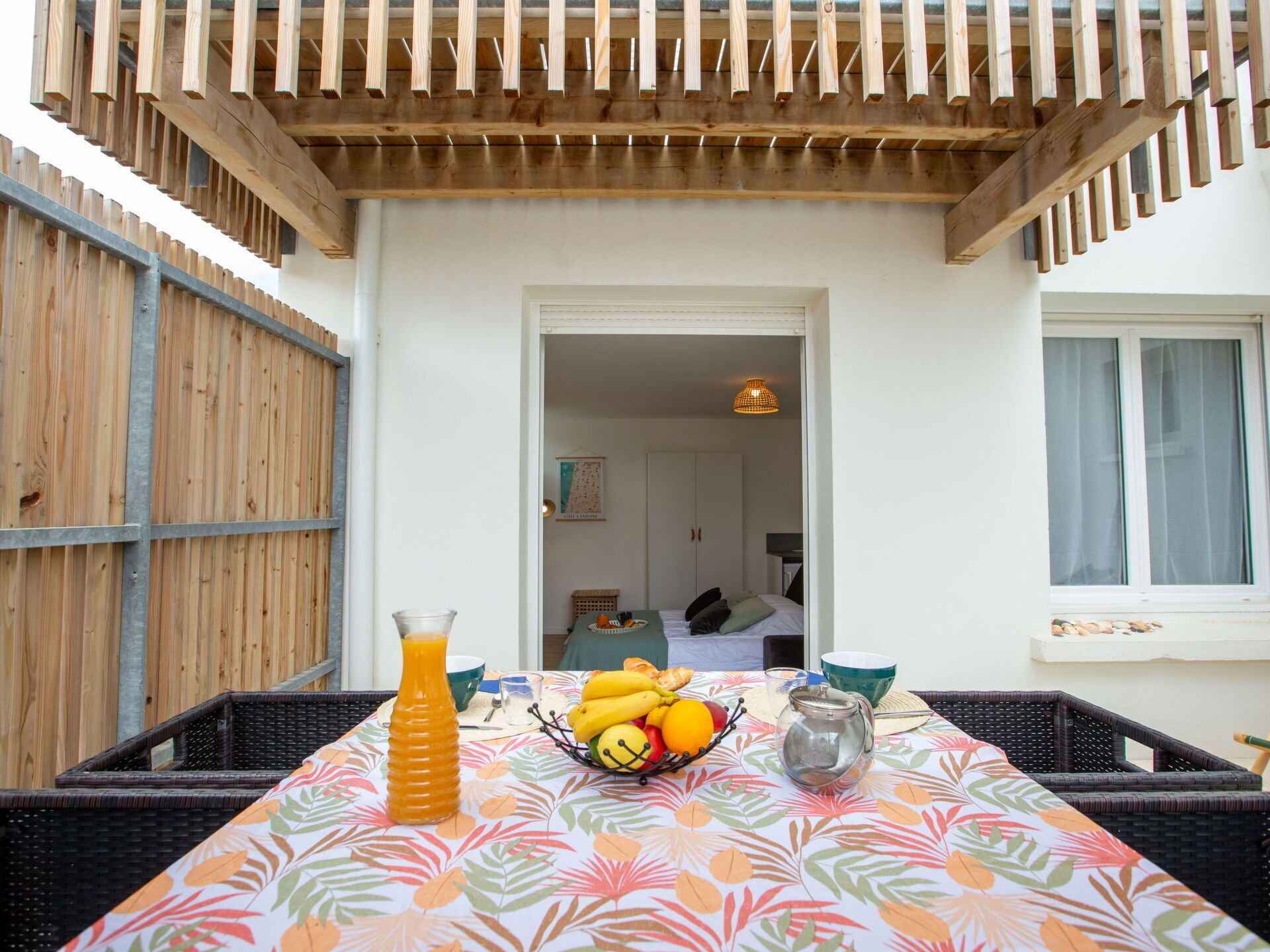 A dining area with a table set for two, featuring a fruit bowl, a pitcher, and a glass of orange juice.