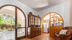 Eine Küche mit Holzausstattung, einem Kühlschrank und einem Fernseher. Ein braunes Ledersofa mit Kissen ist ebenfalls vorhanden.