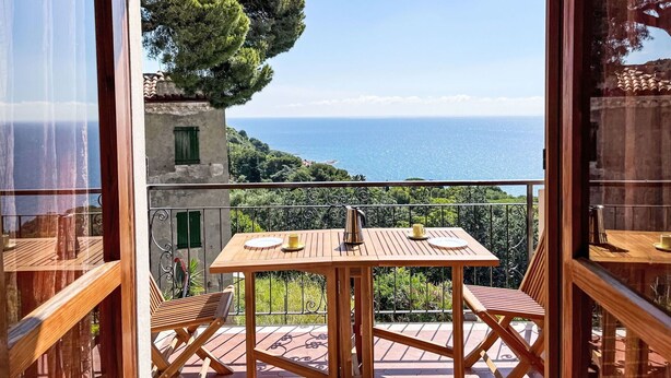 A wooden table and chairs on a balcony with a view of the sea. - Lovely apartment for 3 guests with pool, TV, balcony and pets allowed (Cipressa)