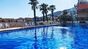 A swimming pool with clear blue water, surrounded by white lounge chairs and palm trees. - Lovely apartment for 3 guests with pool, TV, balcony and pets allowed (Cipressa)