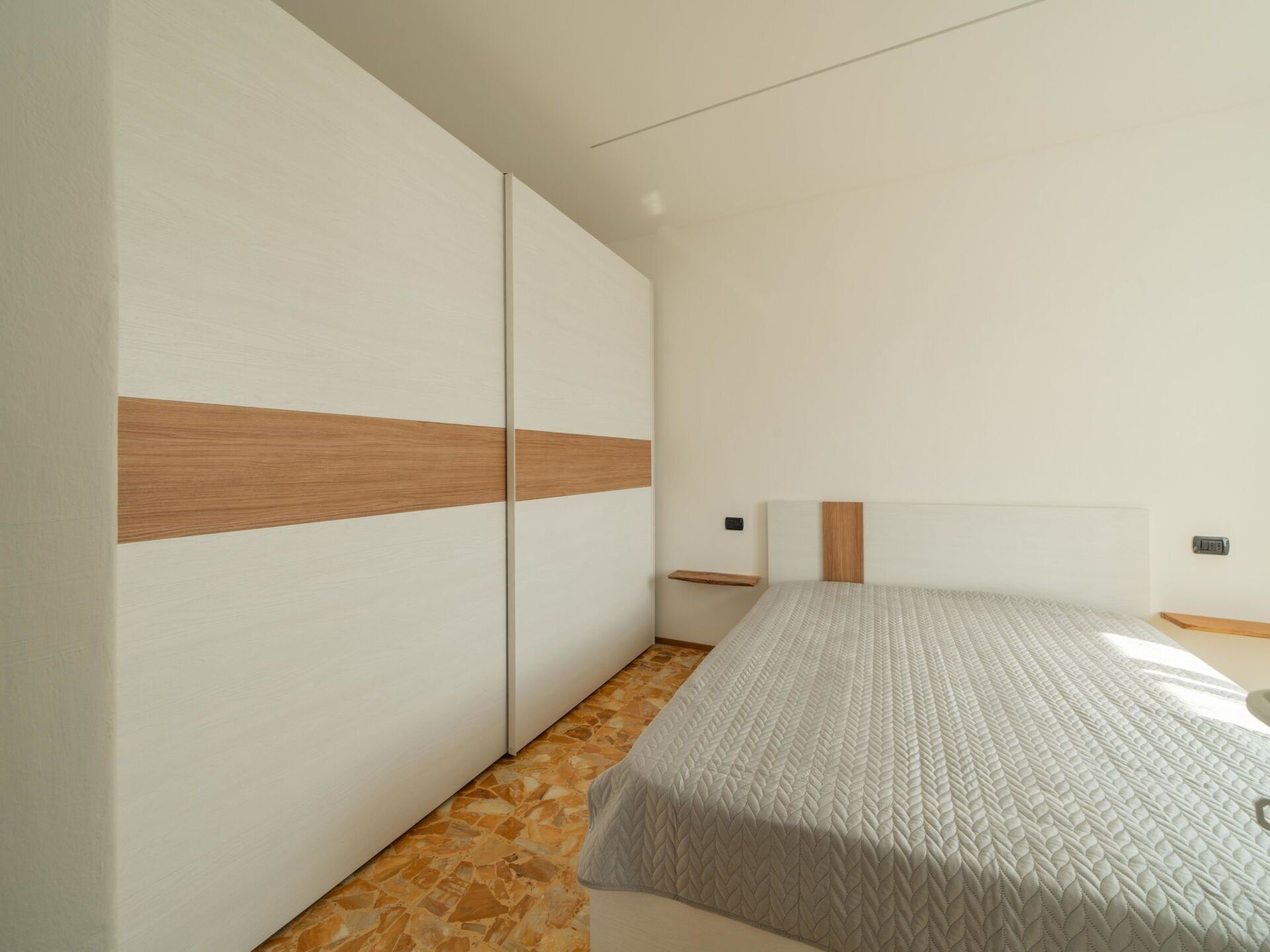Un dormitorio con cama, armario y mesita de noche.