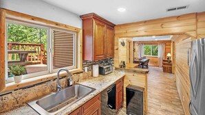 Una cocina moderna con encimeras de granito, armarios de madera, un lavamanos de acero inoxidable y un lavavajillas integrado.