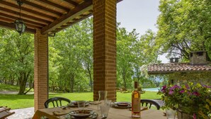 Ein Essbereich im Freien mit einem Tisch für zwei Personen, umgeben von Ziegelstützen, mit Blick auf einen üppigen Garten und einen Pool.