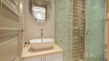 A bathroom with a white sink, a round mirror, and a glass shower enclosure.