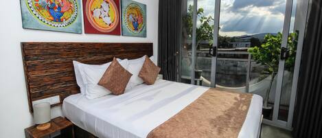 A hotel room with a large bed, a wooden headboard, and a balcony with a view of the sky and clouds.
