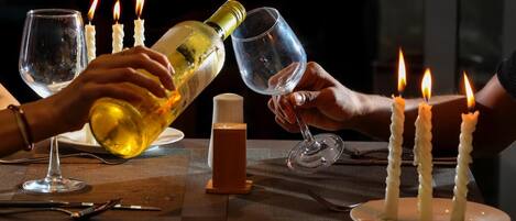 A dining table with wine glasses, a bottle of wine, and lit candles.