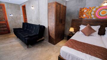 Habitación de hotel con cama, sofá, armario y un cuadro en la pared.