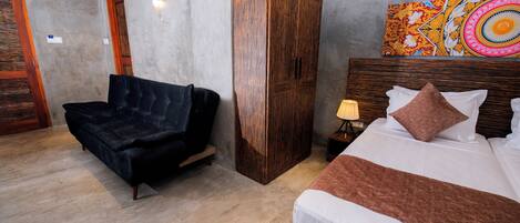 A hotel room with a bed, a sofa, a wardrobe, and a painting on the wall.
