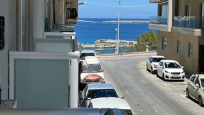 Eine enge Straße mit geparkten Autos und Blick aufs Meer.