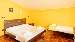 A room with a large bed, a smaller bed, wooden flooring, and a bright yellow wall. - Cosy apartment in villa for 4 people with A/C, WIFI, pool, TV, patio and pets allowed (Silvi)