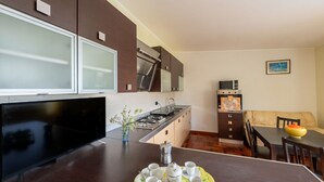 A modern kitchen with a dining area, a flat-screen TV, and a table set with cups and a tray. - Cosy apartment in villa for 4 people with A/C, WIFI, pool, TV, patio and pets allowed (Silvi)