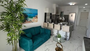 Un salon moderne avec un canapé de couleur turquoise, une grande plante en bambou et un tableau représentant une scène de plage.
