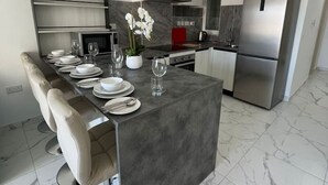 Une cuisine moderne dotée d’un îlot central, d’appareils électroménagers en acier inoxydable et d’un revêtement de sol en marbre.