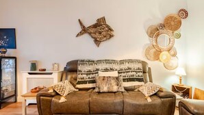 Ein Wohnzimmer mit einem braunen Ledersofa, dekorativen Kissen mit Muster, einer Wanddekoration im Fischdesign und einer Wand voller gewebter Körbe.