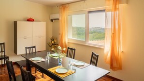 Un coin repas avec une table dressée pour quatre personnes, un meuble blanc et une fenêtre avec des rideaux.