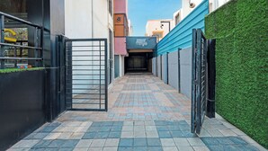 A narrow alleyway with tiled flooring, a metal gate, and a building with a blue awning. - FabHotel Kas (Chhatrapati Sambhajinagar)
