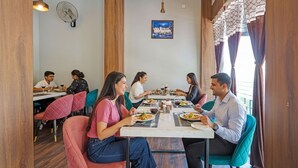 A restaurant with wooden accents, a fan, and a framed picture on the wall. - FabHotel Kas (Chhatrapati Sambhajinagar)