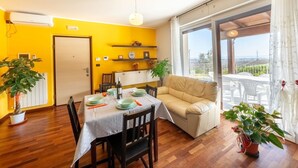 A dining area with a table set for two, a sofa, and a balcony with a view.