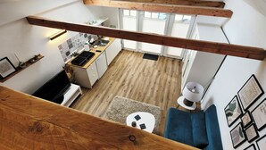 Une cuisine de style loft, dotée de hauts plafonds, de poutres en bois, d’une verrière et offrant une vue sur l’espace de vie adjacent.
