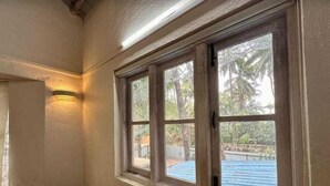 Ein Zimmer mit großem Fenster und Blick auf einen Garten mit Pool und Palmen.