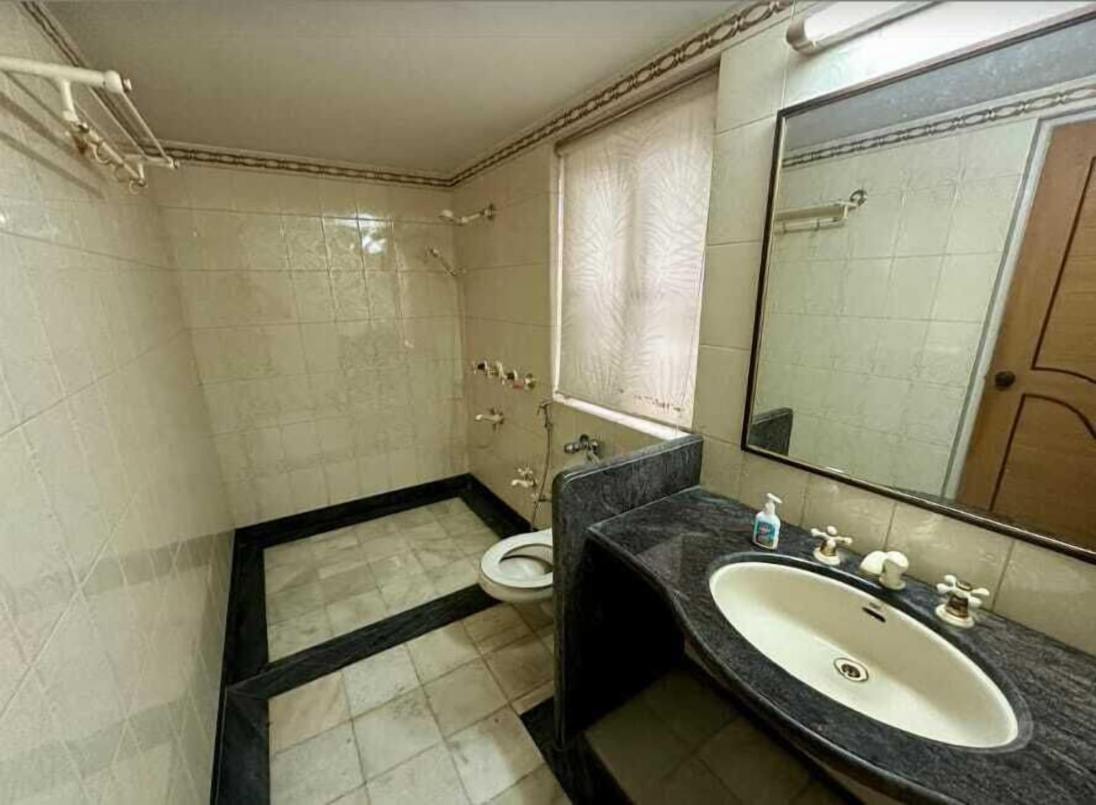 Ein Badezimmer mit Dusche, Toilette, Waschbecken und Spiegel.
