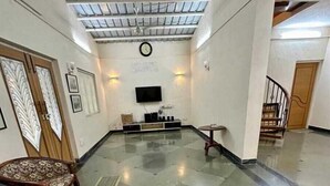 Eine geräumige Lobby mit hoher Decke, einem an der Wand montierten Flachbildfernseher und einer Sitzecke mit einer Holzbank und einem Ledersessel.