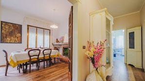 Un comedor con piso de madera, una mesa dispuesta para cuatro comensales y un jarrón de flores.