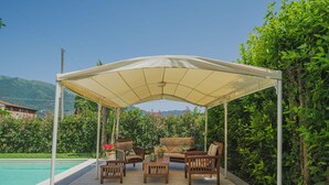 Un patio al aire libre con un espacio de estar cubierto y una piscina.