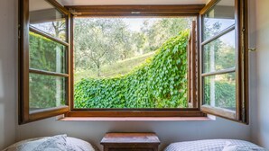 Ein Schlafzimmer mit einem großen Fenster mit Blick auf einen üppigen grünen Garten.