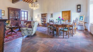 A spacious room with a high ceiling, a chandelier, a dining table set for six, and a painting on easel.